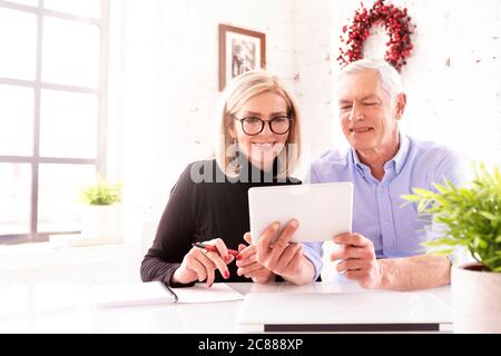 Shot of mature couple using digital tablet while sitting at desk at home. Stock Photo