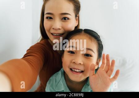 Happy Chinese mother with cute girl waving towards camera Stock Photo