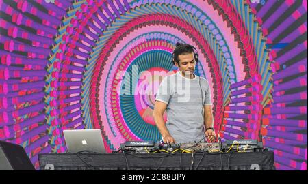 A professional DJ playing music at a festival using digital DJ turntables and abstract visuals in the background Stock Photo
