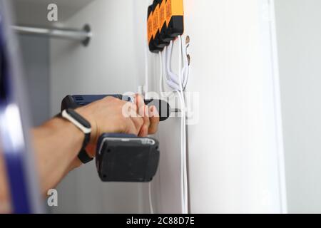 Master holds screwdriver in his hands and drills hole Stock Photo