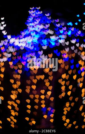 Multi-colored heart-shaped lights in a vertical image with useful black background. Background for Christmas or Valentine Stock Photo
