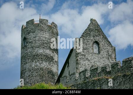 Bezdez, Czech Republic - July 19 2020: Tower and a house, part of the medieval castle made of grey stones standing on a hill. Sunny day with blue sky. Stock Photo