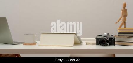 Close up view of worktable with digital devices, camera, stack of books and stationery on white table Stock Photo