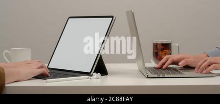 Cropped shot of two female working with mock up digital devices on white table in co working space Stock Photo