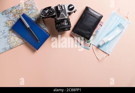 Conceptual still life with various objects related to travel and mask, on pink background. Travel concept during the covid19 coronavirus pandemic. Stock Photo