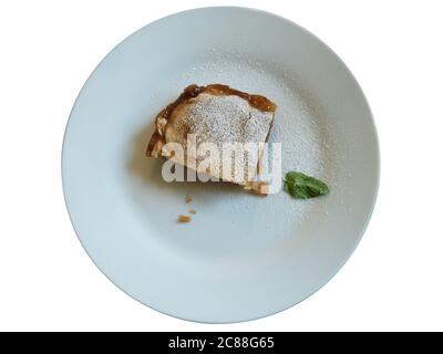Piece of apple pie on white plate, decorated with icing sugar and mint leaf. Isolated on white background. Stock Photo