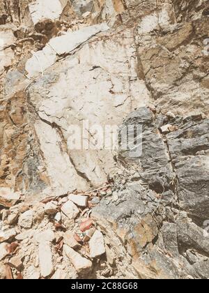 Natural background. Closeup edged shabby cliff cracks. Gray-brown stone rock texture of mountains. Vintage and faded matt style colour in tinted photo Stock Photo