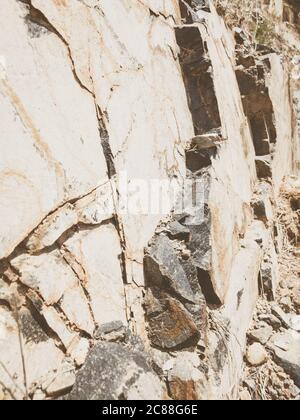 Natural background. Closeup edged shabby cliff cracks. Gray-brown stone rock texture of mountains. Vintage and faded matt style colour in tinted photo Stock Photo