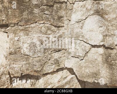 Natural background. Closeup edged shabby cliff cracks. Gray-brown stone rock texture of mountains. Vintage and faded matt style colour in tinted photo Stock Photo