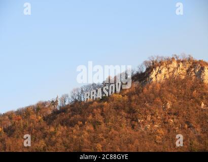 Brasov name, clearly seen on the mountain surrounded by autumn forest. Stock Photo