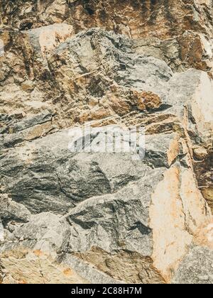 Natural background. Closeup edged shabby cliff cracks. Gray-brown stone rock texture of mountains. Vintage and faded matt style colour in tinted photo Stock Photo