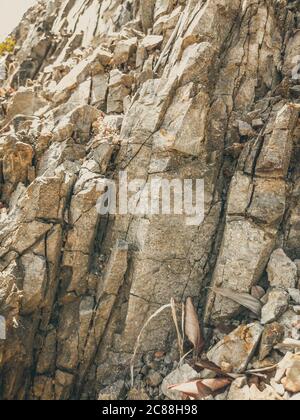 Natural background. Closeup edged shabby cliff cracks. Gray-brown stone rock texture of mountains. Vintage and faded matt style colour in tinted photo Stock Photo