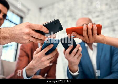 Male and female diverse hands holding cell phones, multiracial business people using smartphones applications software, users and devices concept Stock Photo