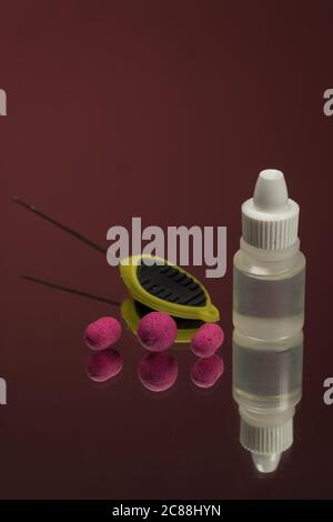 Close up view of crimson boilies, flavor bottle, fishing baits for carp isolated on red background. Stock Photo