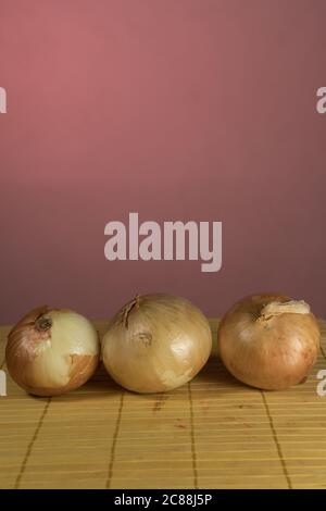 Three onions on board cutting, red background Stock Photo
