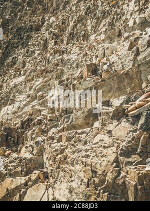 Natural background. Closeup edged shabby cliff cracks. Gray-brown stone rock texture of mountains. Vintage and faded matt style colour in tinted photo Stock Photo