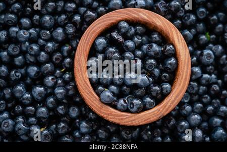 Wooden bowl full of fresh blueberries with herbs. Top view. Ripe blueberries with copy space for text. Fresh blueberries scattered. Stock Photo