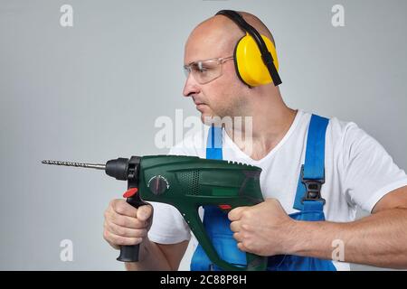 grown man with a drill in his hands . photo session in the Studio on a white background. the concept of the construction Stock Photo