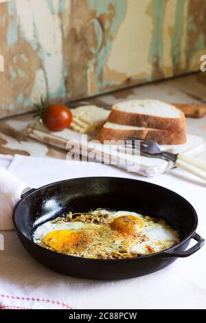 Fried eggs with onions and spices in a cast iron skillet. Stock Photo