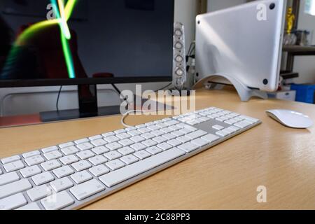 Detailed view of a cradled laptop computer used on a office desk with an extended keyboard, wireless mouse and computer monitor in use. Stock Photo
