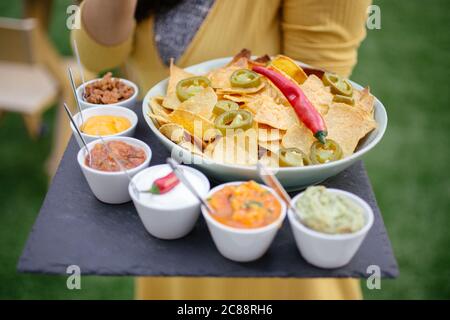 Closeup shot of nachos with chilies on a bowl with different kinds of dip on the side Stock Photo