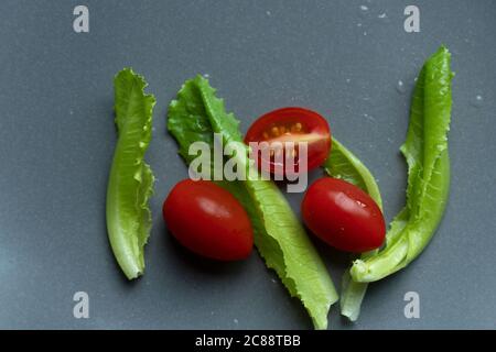 colorful fresh green romaine lettuce and red tomato food vegetable on grey dark plate background Stock Photo