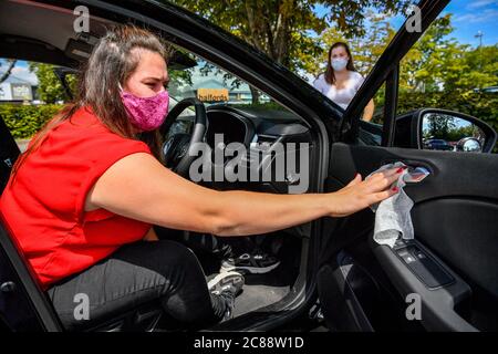 Driving instructor Kayleigh Nurse uses a antibacterial wipe on the surfaces of her car as she changes driving positions after her student Roisin Clarke (right), 17, passed her driving test in Yeovil, Somerset. Driving tests, which were suspended across the UK in March, have restarted in England with a huge backlog after hundreds of thousands of tests were delayed or cancelled due to the coronavirus lockdown. Stock Photo