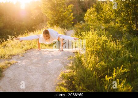 Concentrated sporty woman performing Firefly pose. Girl doing yoga exercises, leaning on hands Stock Photo