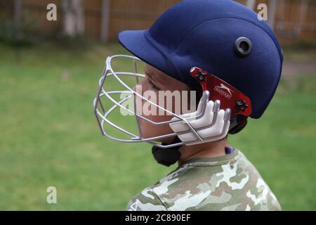 Child in cricket gear playing cricket practice at home in UK garden during lockdown, 2020 Stock Photo