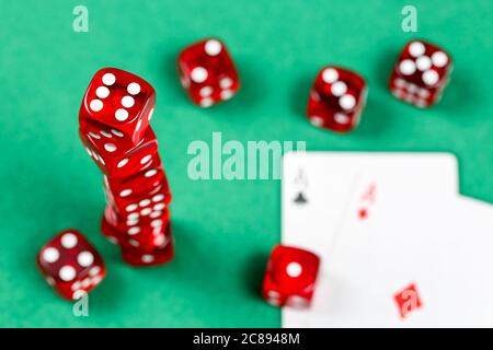 stack of red dice and playing cards on green felt texture Stock Photo