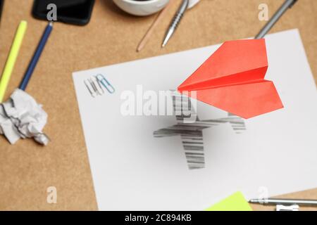 red paper plane flying over office desk, sketch of plane underneath, creativity concept Stock Photo