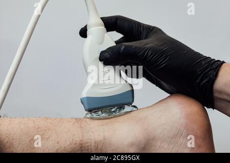 Detail of hand doing an ultrasound scan of the achilles tendon Stock Photo