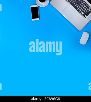 Top view laptop, mouse, smart phone and coffee on blue background. Laptop, mouse, mobile phone, black coffee isolated on blue background with copy spa Stock Photo