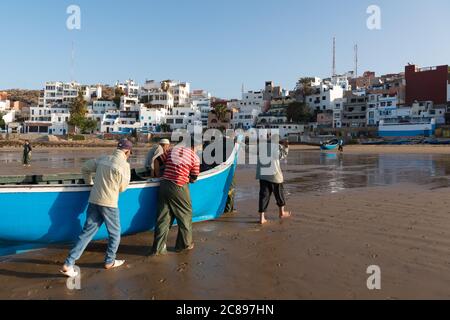 Fishermen bringing in the daily catch on the beach in Taghazout, Morocco Stock Photo