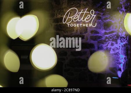 Neon light text "Better together" on a stone wall with bokeh lights effect Stock Photo