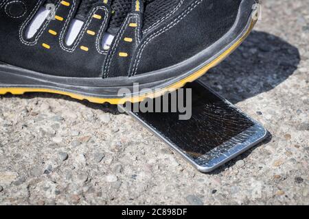 Trampled phone, Leg standing on the smartphone, Cracked display Stock Photo