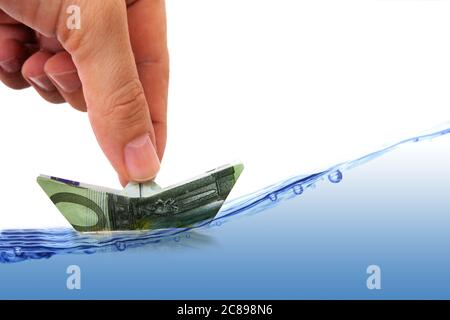 hand with money boat on wavy water Stock Photo