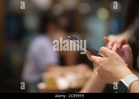 close up woman's hands using smart phone. Colorful bokeh background Stock Photo