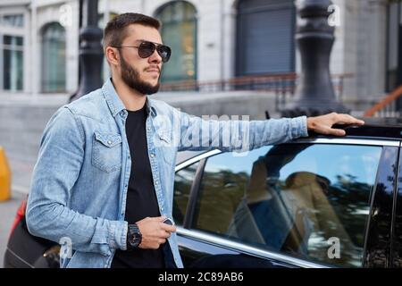 pensive serious macho standing near his vehicle. close up side view photo Stock Photo