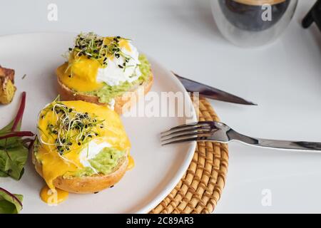 Poached eggs over the bread bun with mashed avocado. Stock Photo