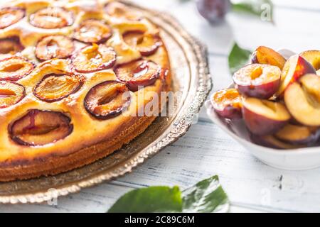 Homemade plum cake in vintage plate on wooden table. Plums pie with sugar powder Stock Photo