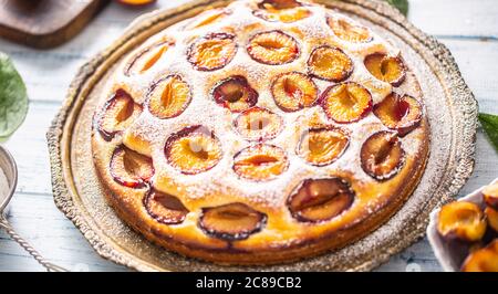 Homemade plum cake in vintage plate on wooden table. Plums pie with sugar powder Stock Photo