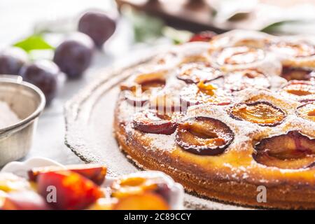 Homemade plum cake in vintage plate on wooden table. Plums pie with sugar powder Stock Photo