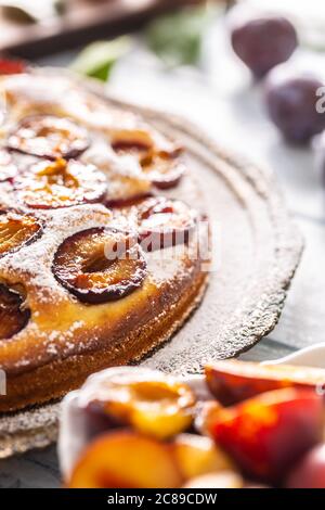 Homemade plum cake in vintage plate on wooden table. Plums pie with sugar powder Stock Photo