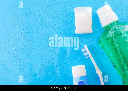 Dental care and oral hygiene concept with a bottle of green mouthwash, toothbrush, dental floss and tube of toothpaste soaked in water droplets, isola Stock Photo