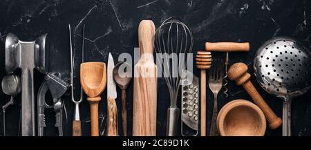 Various kitchen utensils and tools on a black stone background, banner. Top view, flat lay. Collection kitchenware