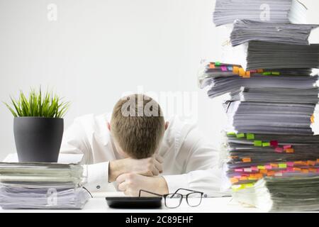 Office worker was very tired and fell asleep at workplace, head lies on table Stock Photo