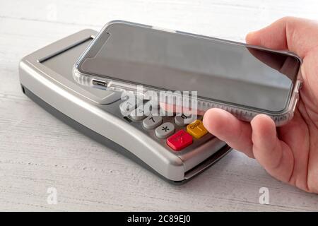 Contactless payment, digital wallet and nfc technology conceptual idea with smartphone making a transaction to credit card terminal isolated on white Stock Photo