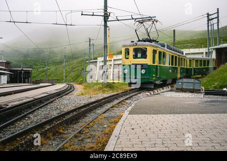 Kleine Scheidegg, Bernese Oberland, Switzerland - July 31 2019 : Old electrical green and yellow train of the Wengernalpbahn (WAB) with pantograph up Stock Photo