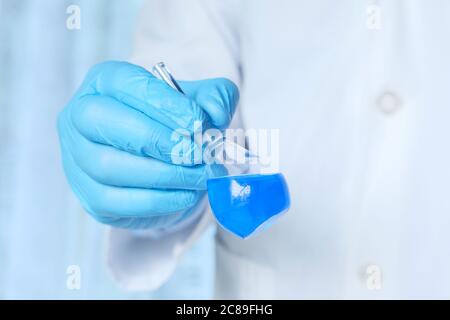 scientist in blue gloves doing chemical test in laboratory Stock Photo
